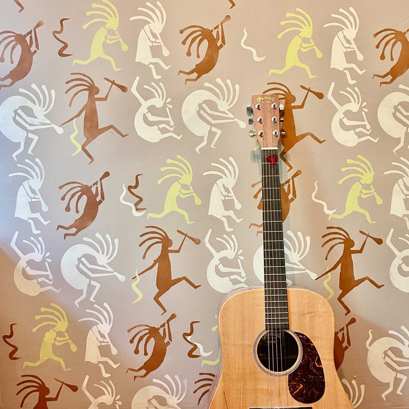 south western kokopelli flute player in various positions and colors painted on wall
